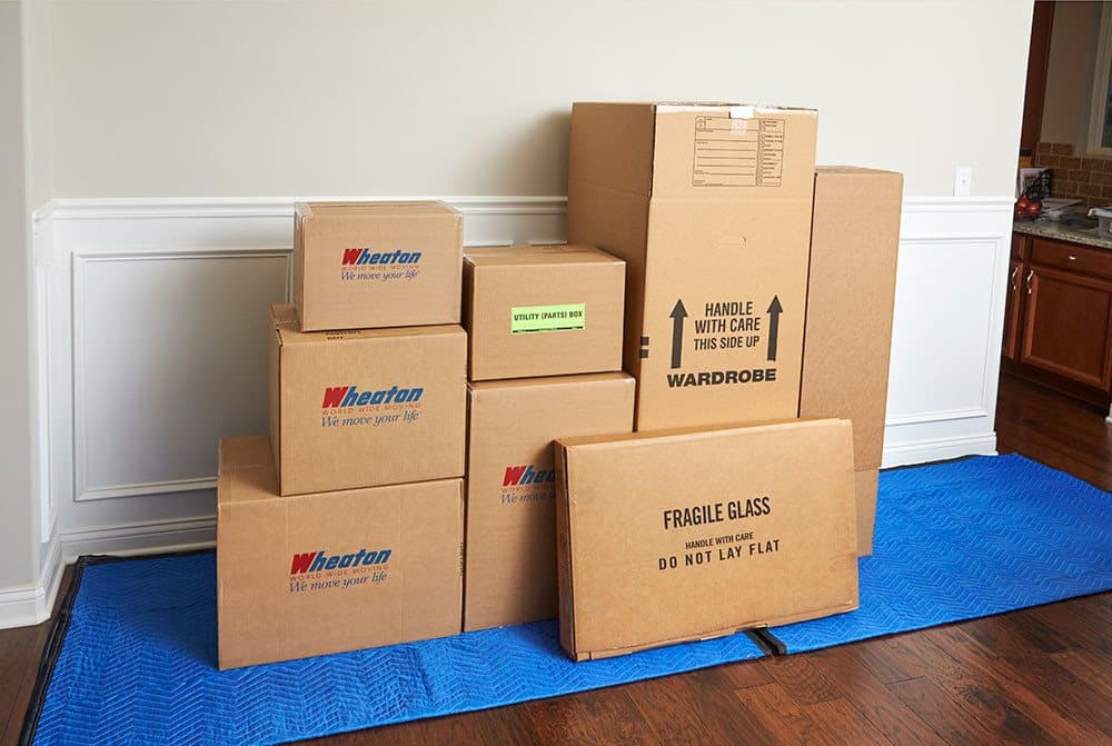 Neatly packed and labeled Wheaton moving boxes stacked on a protective blanket inside a home
